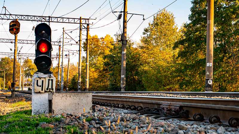 A traffic light by a train track.